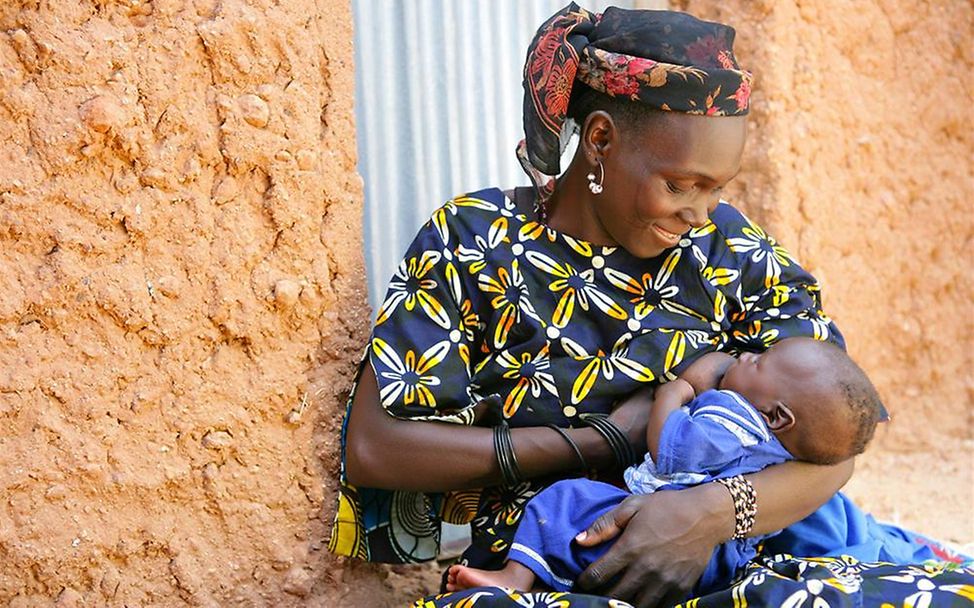 Eine Frau stillt ihr Baby in einem kleinen Ort in Niger.