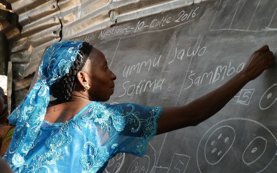 Ummu schreibt im Unterricht ihren Namen auf eine Tafel.