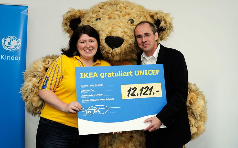 IKEA-Bär Darren mit dem Spendenscheck für UNICEF-Geschäftsführer Schneider