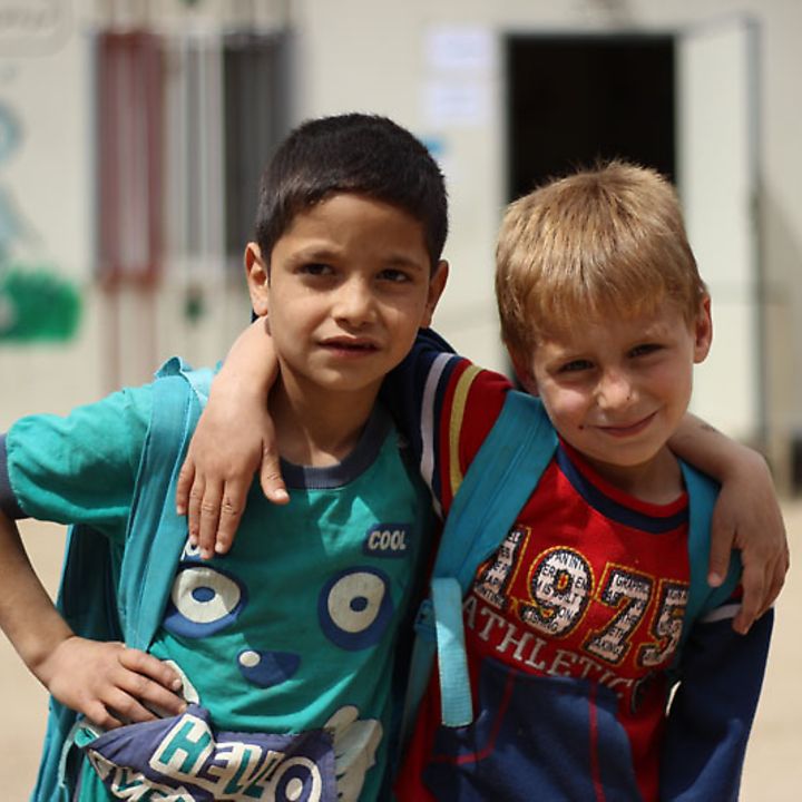 Zwei kleine Jungen stehen Arm in Arm vor ihrer mit Hilfe von UNICEF aufgebauten Schule.