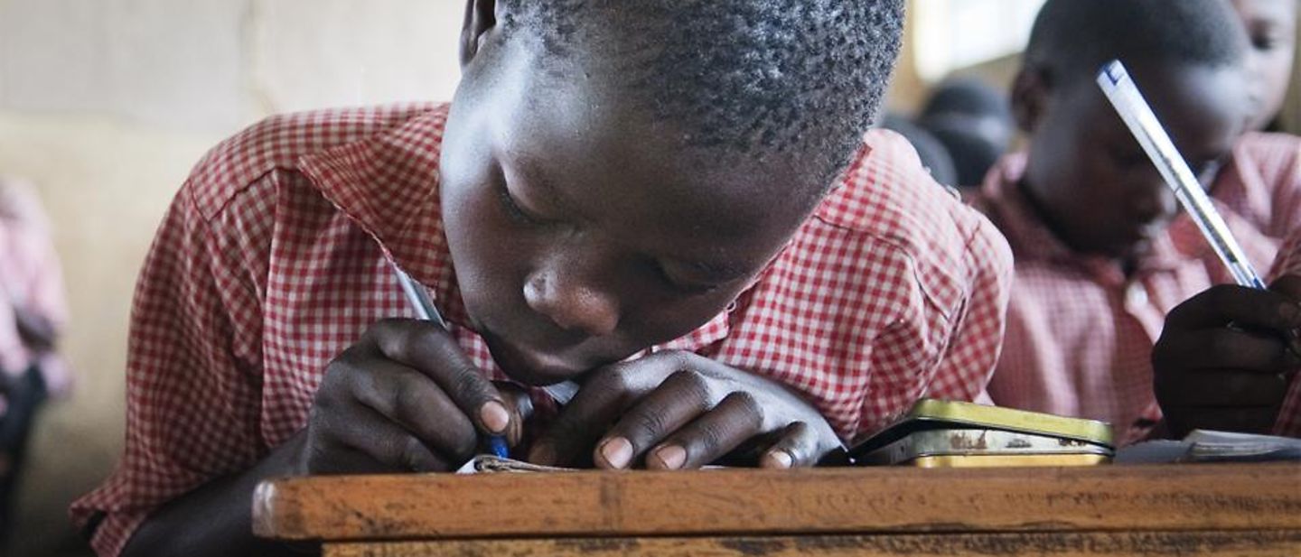 UNICEF in Uganda: Charles schreibt in sein UNICEF-Heft