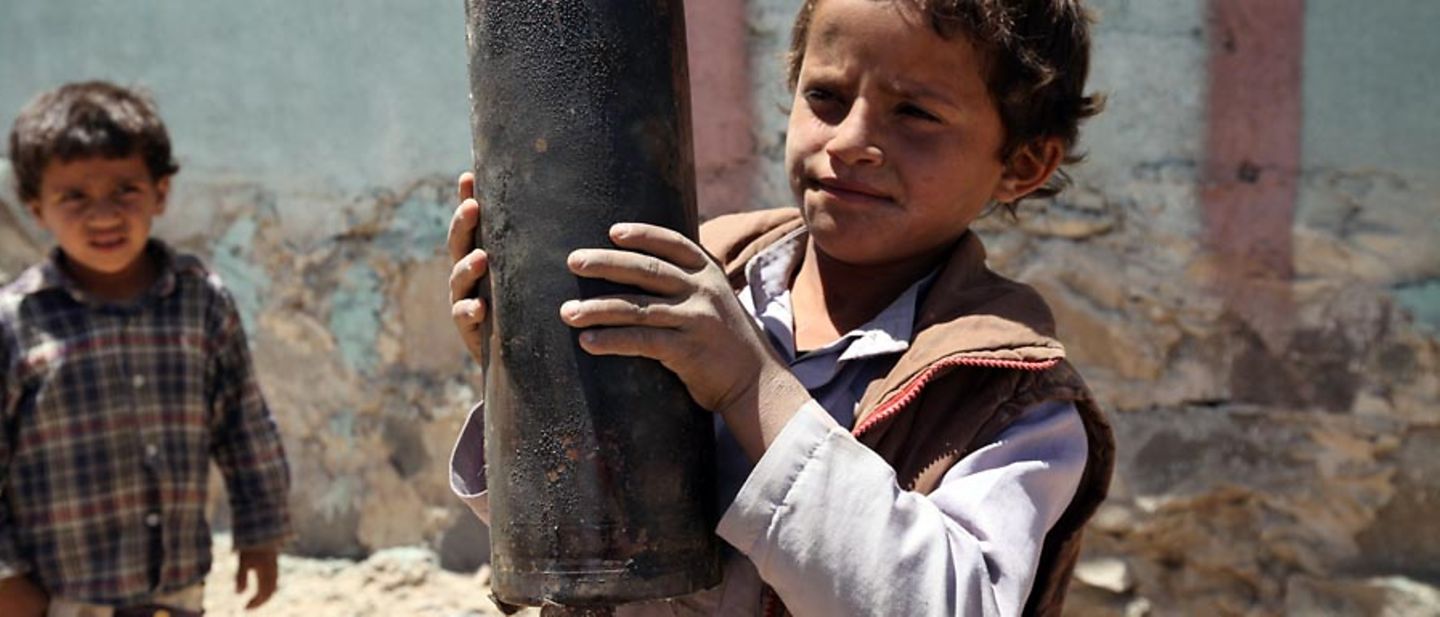 Kinder im Krieg: Ein Junge hält die Reste einer Bombe