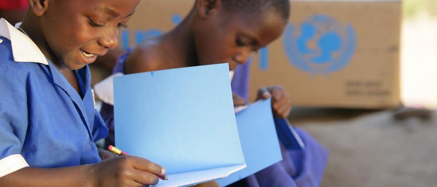 Spenden für Bildungsangebote: Zwei Schulkinder schreiben in von UNICEF bereitgestelltes Lernmaterial.