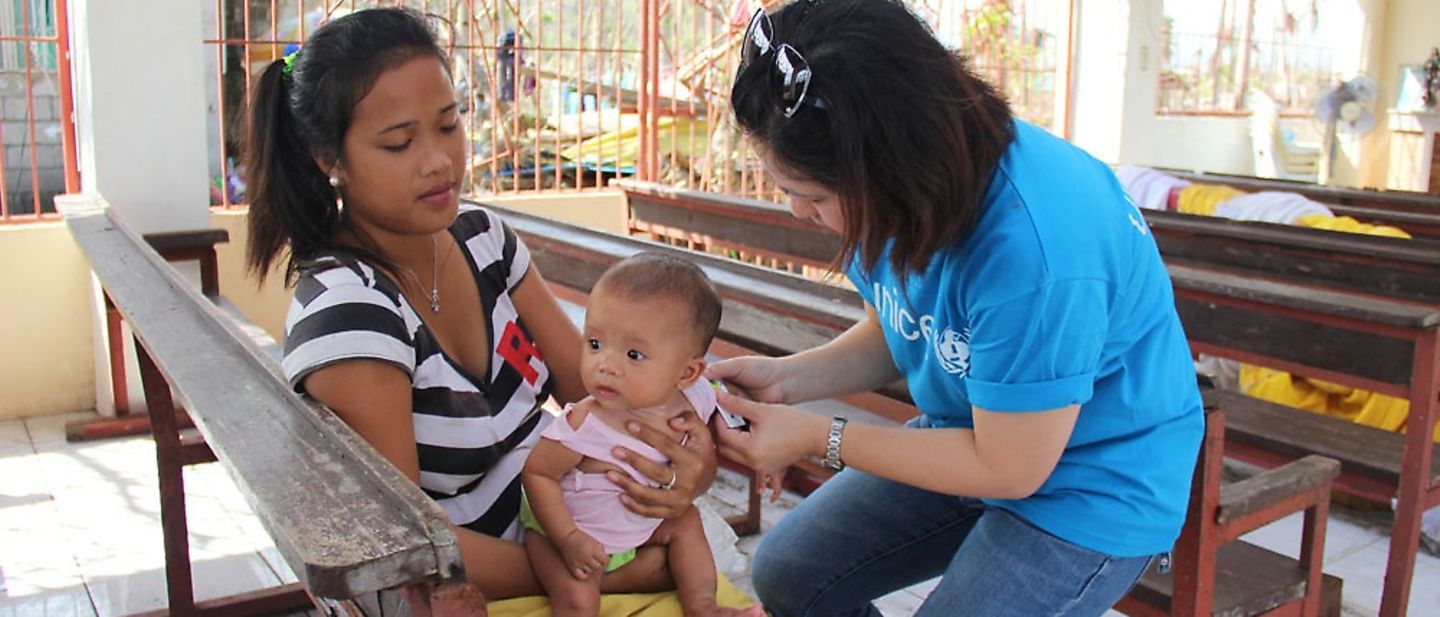 Medizinsche Hilfe: UNICEF-Mitarbeiterin untersucht Jungen