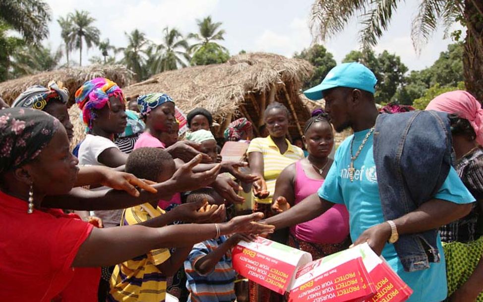 Infektionsgefahr durch Ebolafieber: Ein UNICEF-Helfer verteilt in einem Dorf Infomaterial zu Ebola.