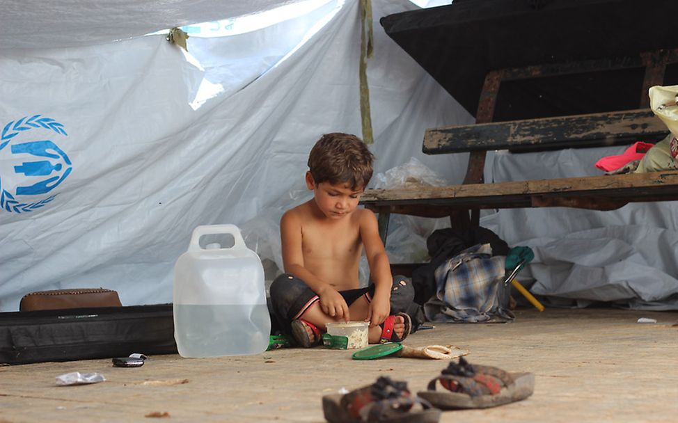 Ein kleiner Junge sitzt vor einem provisorischen Zelt. Er musste mit seiner Familie vor den neusten Angriffen flüchten.