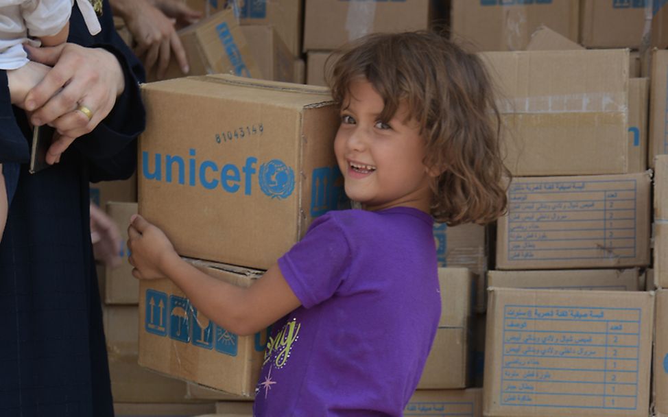 Ein kleines Mädchen holt UNICEF-Hilfsgüter in einer Moschee ab, die ihr und ihrer Familie vorerst als Unterkunft dient.