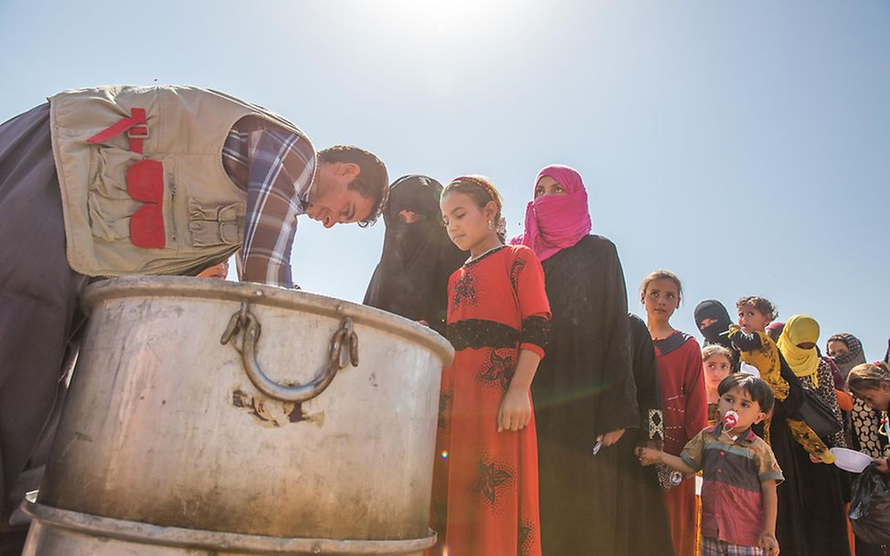 Irakische Frauen und Frauen und Kinder stehen im Debaga Flüchtlingslager in Erbil Schlange, um Lebensmittel zu bekommen.