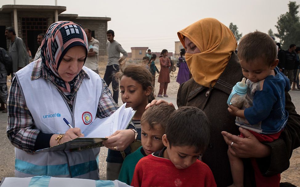 Irak: Kinder und Frauen scharen sich um Isra, eine Mitarbeiterin vom UNICEF-Impfteam.