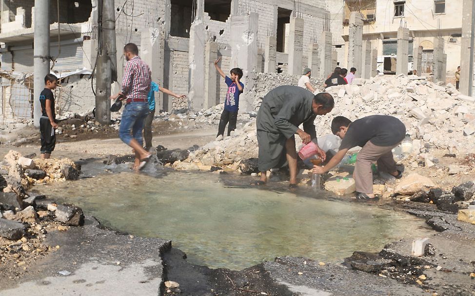 Aleppo: Wasser wird aus einem Bombenkrater abgefüllt