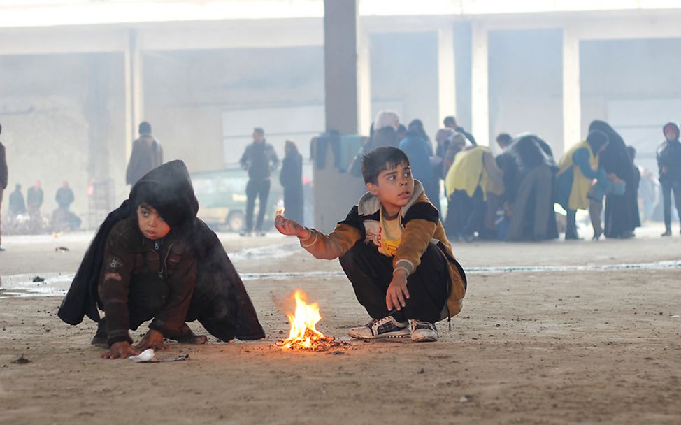 Syrien (Jibreen nahe Aleppo): Zwei Flüchtlingsjungen wärmen sich am Feuer