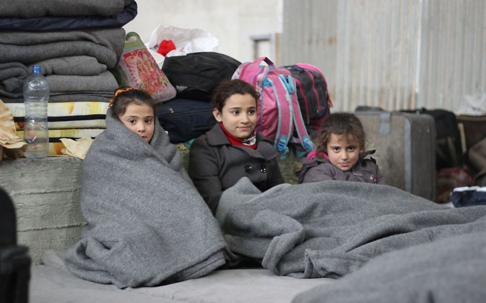 Winter in Syrien: Drei Mädchen wärmen sich mit Winterdecken von UNICEF