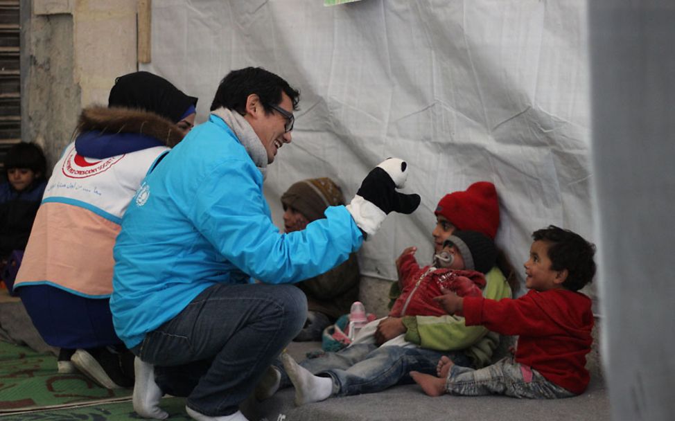 Winter in Syrien: Ein ehrenamtlicher UNICEF-Helfer spielt mit Kindern