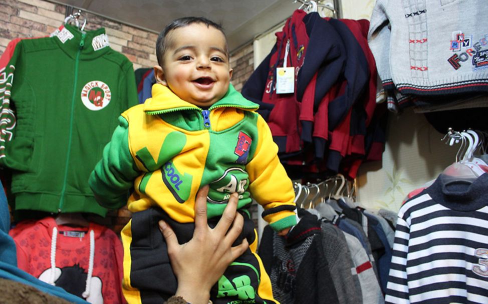 Winter in Syrien: Der einjährige Khaled lacht glücklich in seinen warmen Anziehsachen
