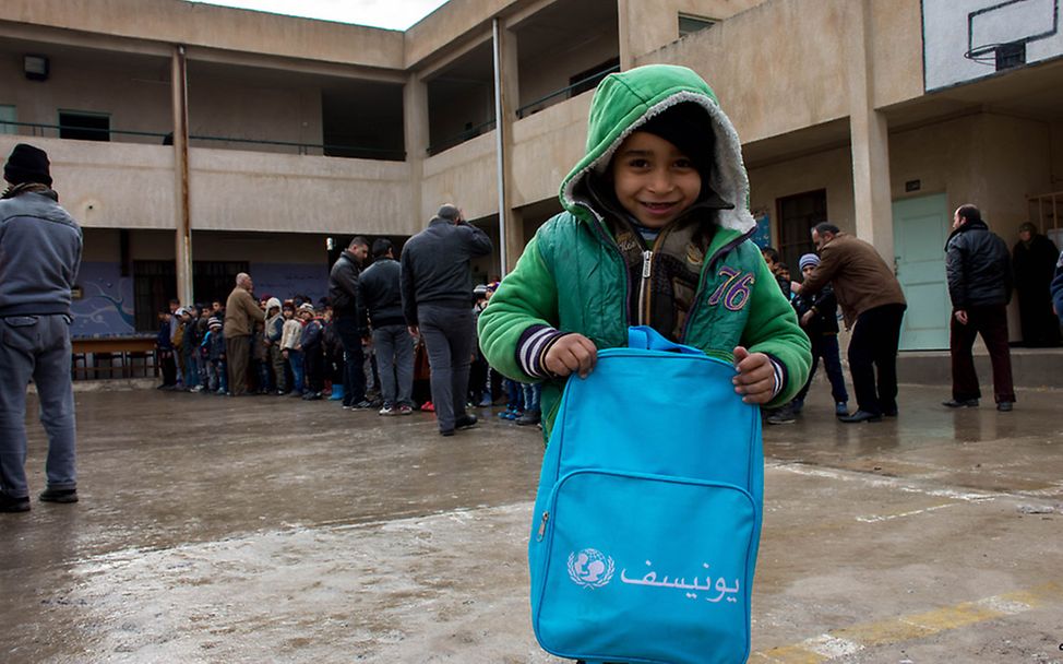 Ein kleiner Junge freut sich über seinen neuen UNICEF-Schulranzen.