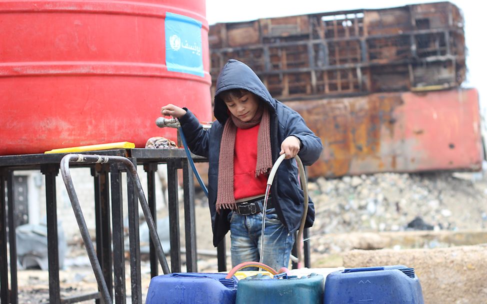 Ein Junge holt an einem UNICEF Wassertank Wasser für seine Familie in Ost-Aleppo.
