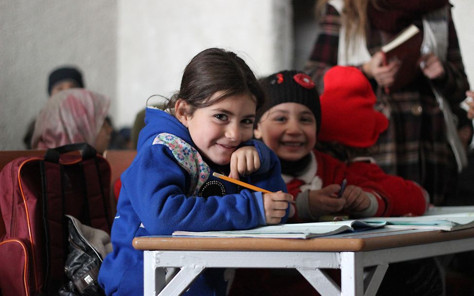 Zwei Mädchen sitzen in West-Aleppo in der Schulklasse und können dank UNICEF den Unterricht besuchen.