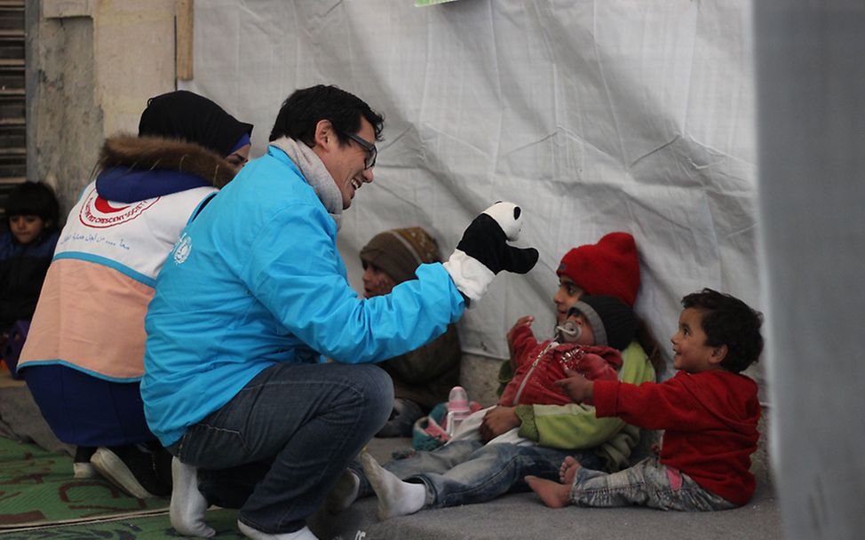 In einem Kinderzentrum in Jibreen spielen UNICEF-Mitarbeiter mit Kindern.