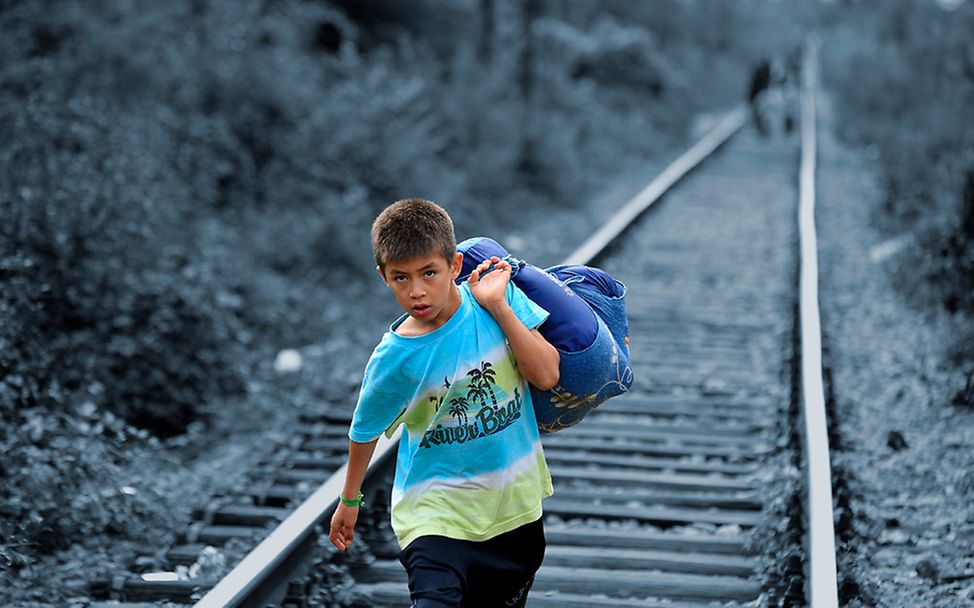 Serbien: Ein kleiner Junge trägt einen Wäschebeutel auf seinen Schultern.