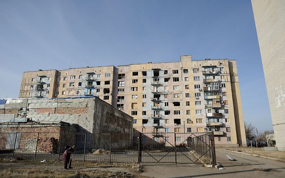 Ukraine-Konflikt: Eine Frau vor einem beschädigten Wohnblock in Avdiivka