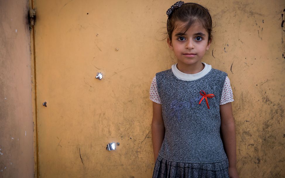 Irak, Mossul: Abrar steht vor ihrer Hauswand, die mit Einschusslöchern übersäht ist.