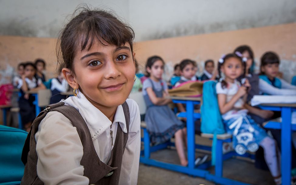 Ein Mädchen lächelt in einer von UNICEF wieder aufgebauten Schule im Irak.