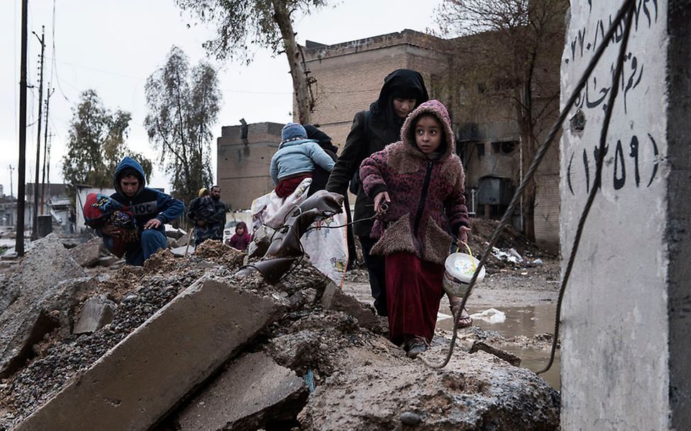 Eine Familie flieht durch Trümmer mit ihrem Hab und Gut vor den Kämpfen in Mossul.