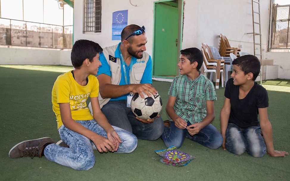 Makani: Drei Jungs mit einem UNICEF-Mitarbeiter auf dem Dach eines Makani-Zentrums