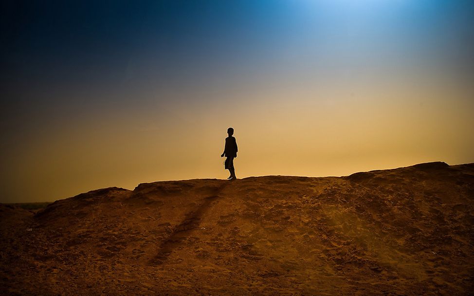 Komplexe Fluchtursachen: Armut, Terror, Klimawandel - ein Junge auf einer Sanddüne (Symbolbild)