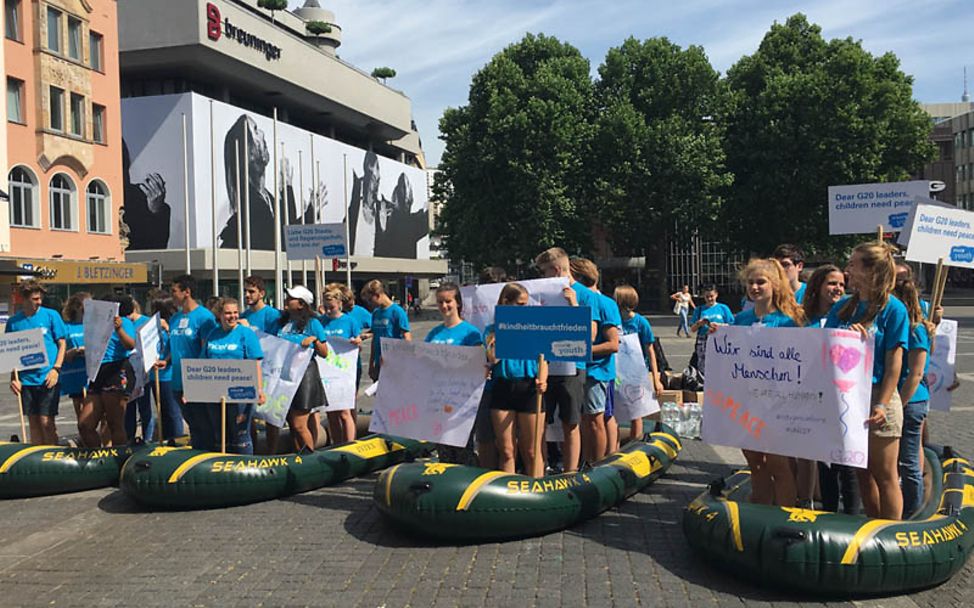 Zum G20: Jugendliche demonstrieren in Schlauchbooten für Frieden für jedes Kind.