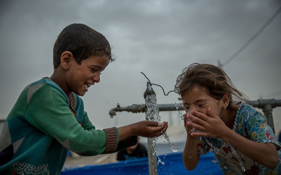 Irak: Zwei Kinder trinken sauberes Wasser aus einem Wassertank