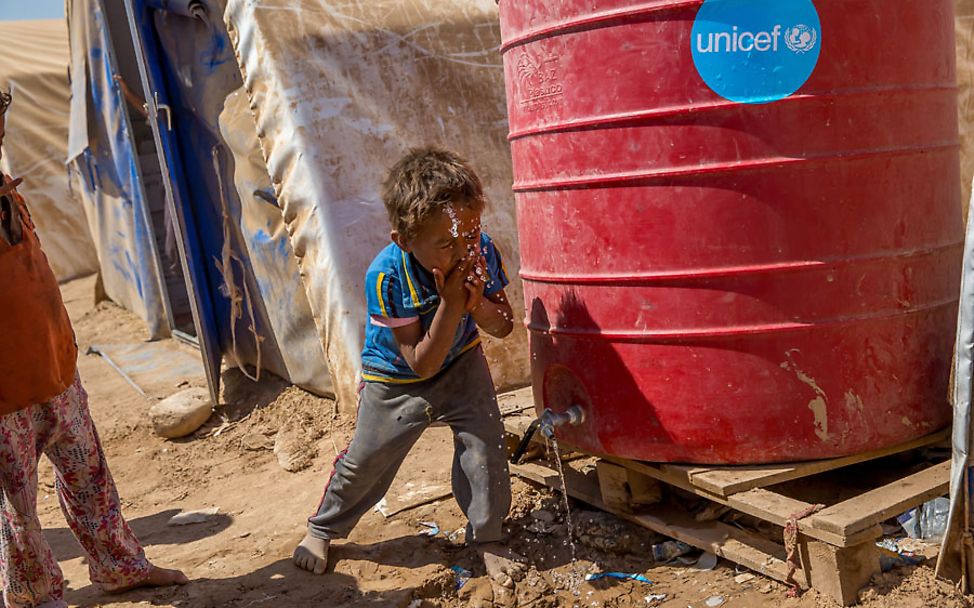 Ein Junge wäscht sich sein Gesicht mit Wasser aus einem UNICEF-Tank