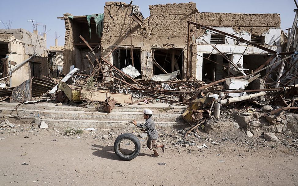 Vor den Ruinen der zerstörten Altstadt von Saada, Jemen, spielt ein Junge mit einem Reifen. 