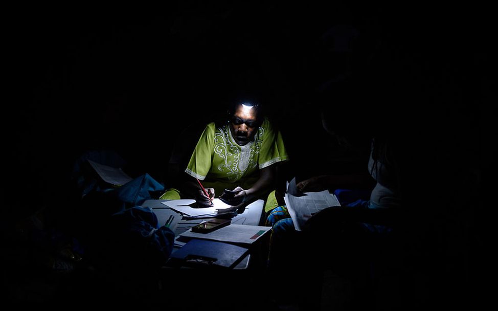 Südsudan: Eine UNICEF-Ernährungswissenschaftlerin macht sich Notizen im Licht einer Taschenlampe