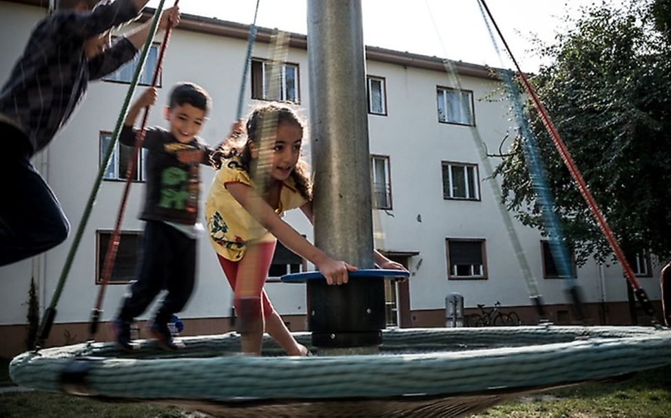 Die drei Kinder einer syrischen Familie spielen vor ihrem Zuhause.