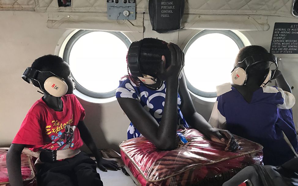 Südsudan: Drei Kinder sitzen in einem Hubschrauber und werden bald ihre Familien wiedersehen