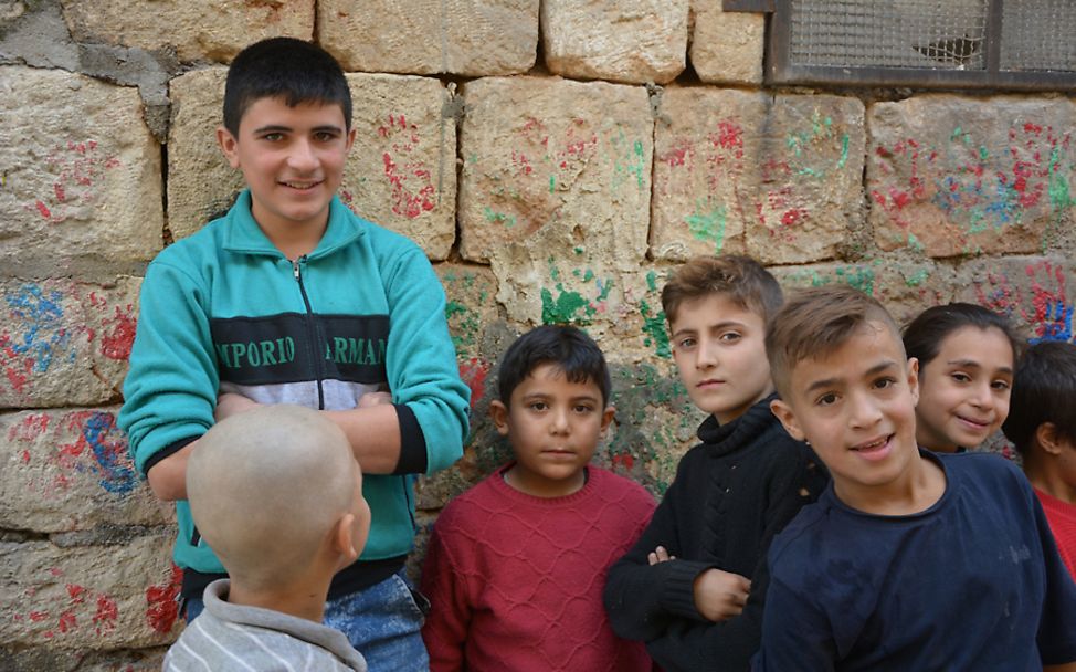 Syrien: Der vierzehn-jährige Saad steht lächelnd an einer Häuserwand