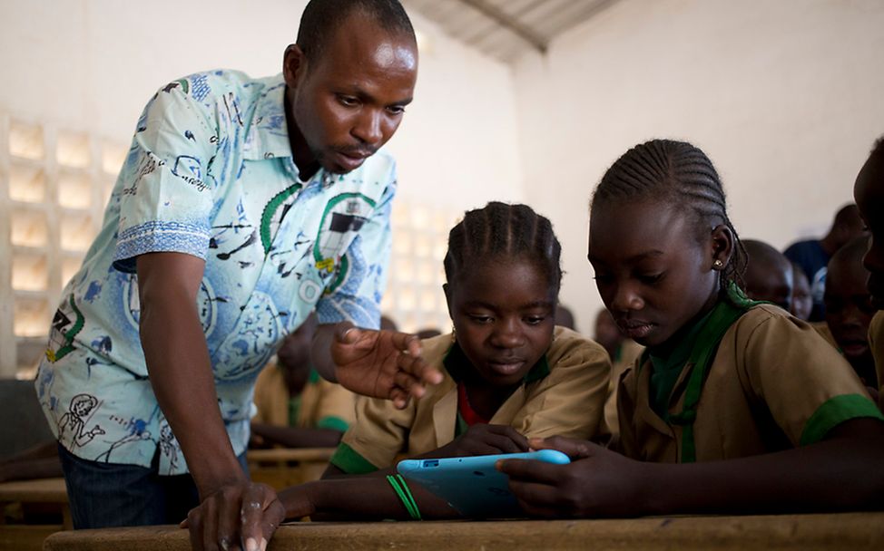 Ein Lehrer erklärt Schülern in Kamerun etwas an einem Tablet.