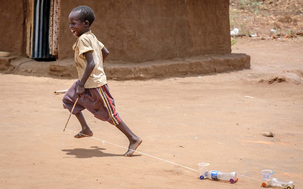 Uganda: Ein Junge rennt mit dem selbstegebauten Autos herum