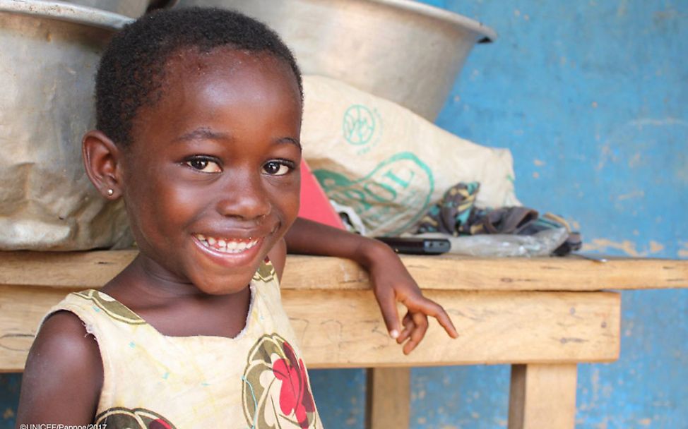 Ghana: Ein Mädchen lehnt lachend an einem Tisch