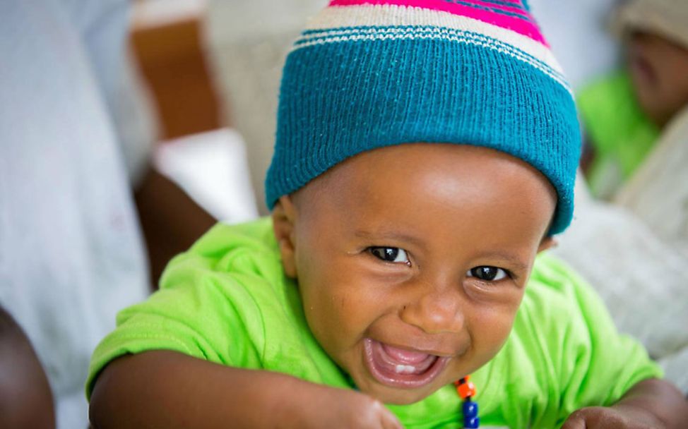 Äthiopien: Ein Baby mit Wollmütze lacht