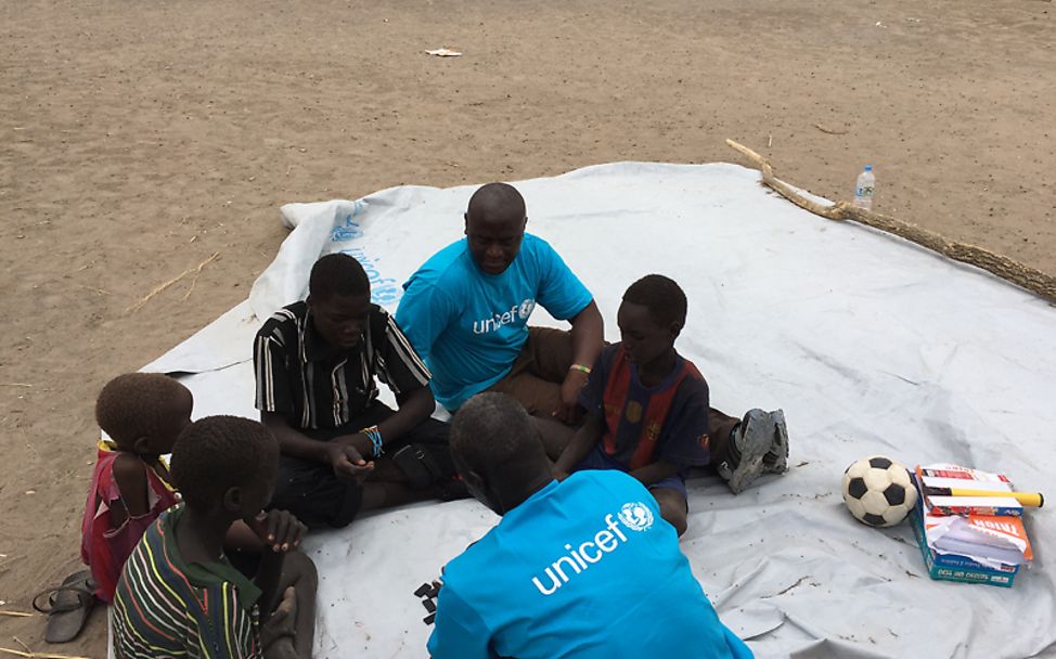 Südsudan: Michael spielt mit Kinder auf einer Plane um sie von schlimmen Erinnerungen abzulenken