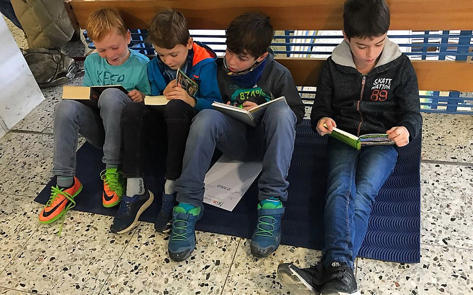 Lesen für UNICEF: Vier Jungs sind ans Geländer gelehnt und lesen ihre Bücher