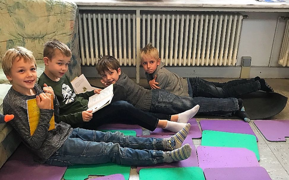 Lesen für UNICEF: Hier haben es sich vier Jungs auf den Matten bequem gemacht