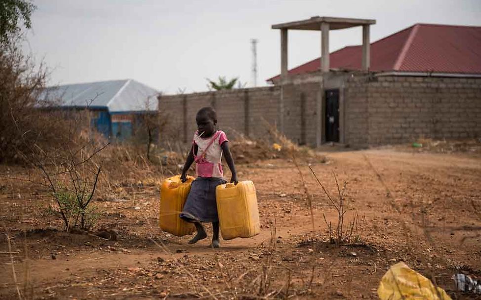 Ein Kind trägt leere Wasserkanister zu einem nahegelegenen Zapfhahn. | © UNICEF/Hatcher-Moore  