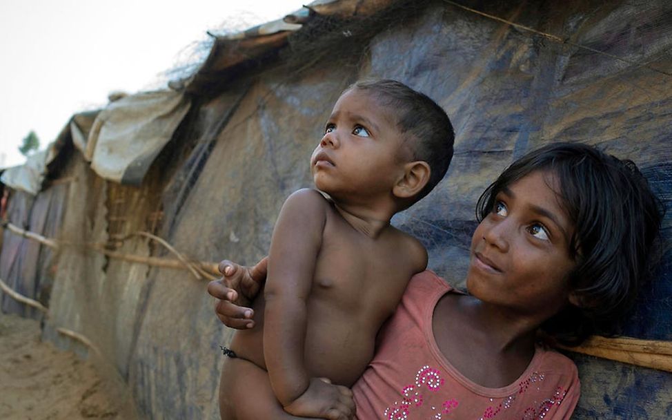 Zwei Rohingya-Kinder in Bangladesch sehen besorgt in Richtung Himmel. 