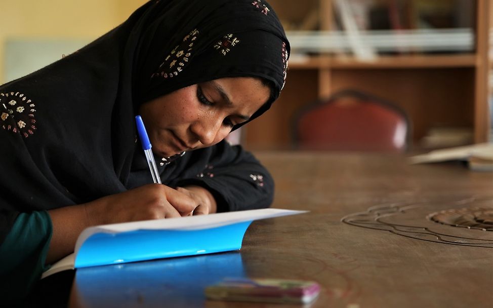 Studie Bildung Afghanistan: Ein Mädchen schreibt in ein UNICEF-Schulheft