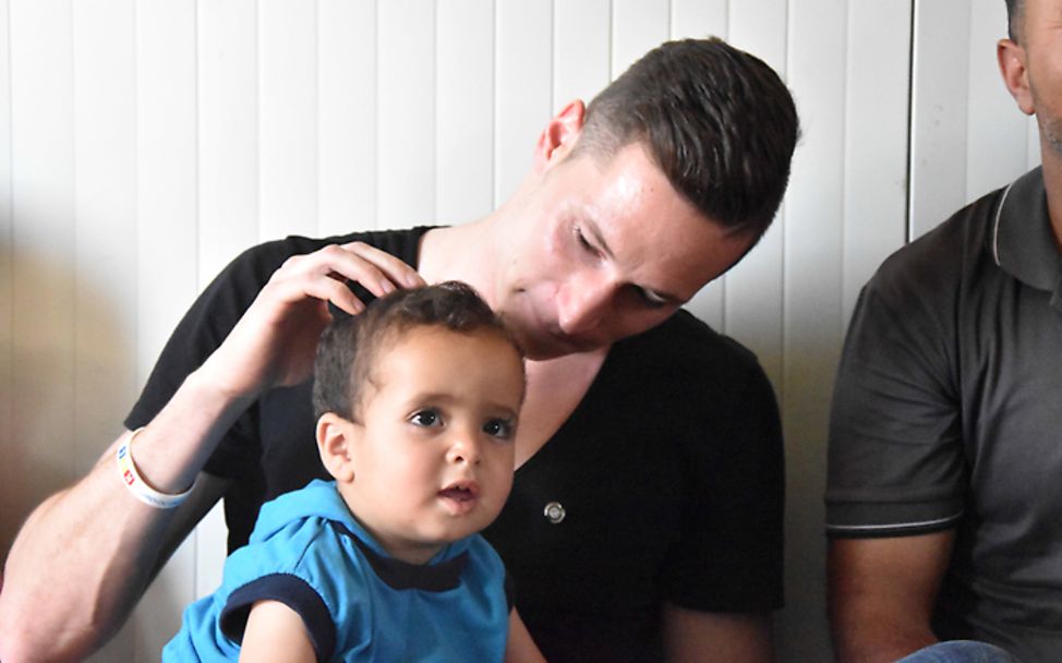 Jordanien: Julian Draxler hält den kleinen Abdullah auf dem Schoß und streichelt ihn.
