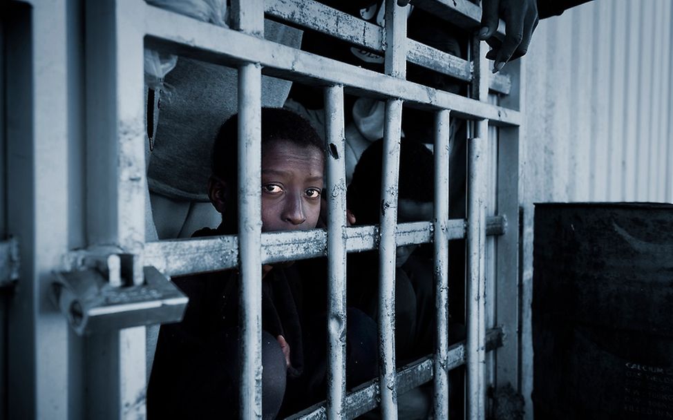 Libyen Flüchtlinge: Ein Junge guckt durch die Gitter eines Lagers in Libyen