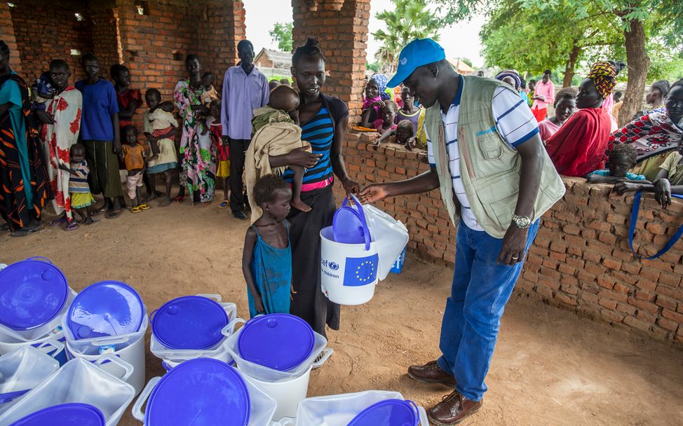 Cholera im Südsudan: Ein UNICEF-Helfer verteilt Wassereimer an eine Familie. 